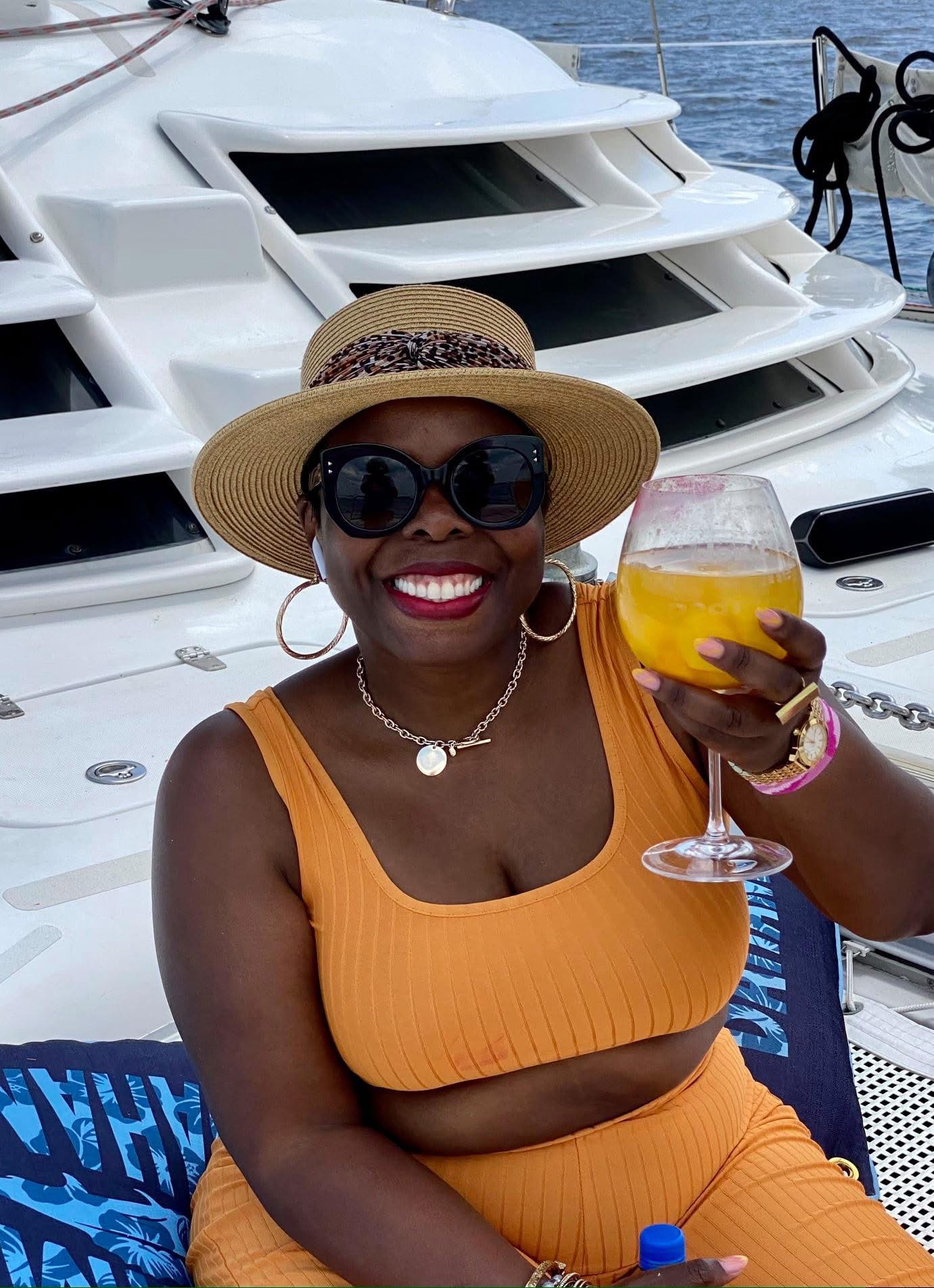 Guest enjoying a drink and smiling on the deck of Now and Zen catamaran on the St Johns River