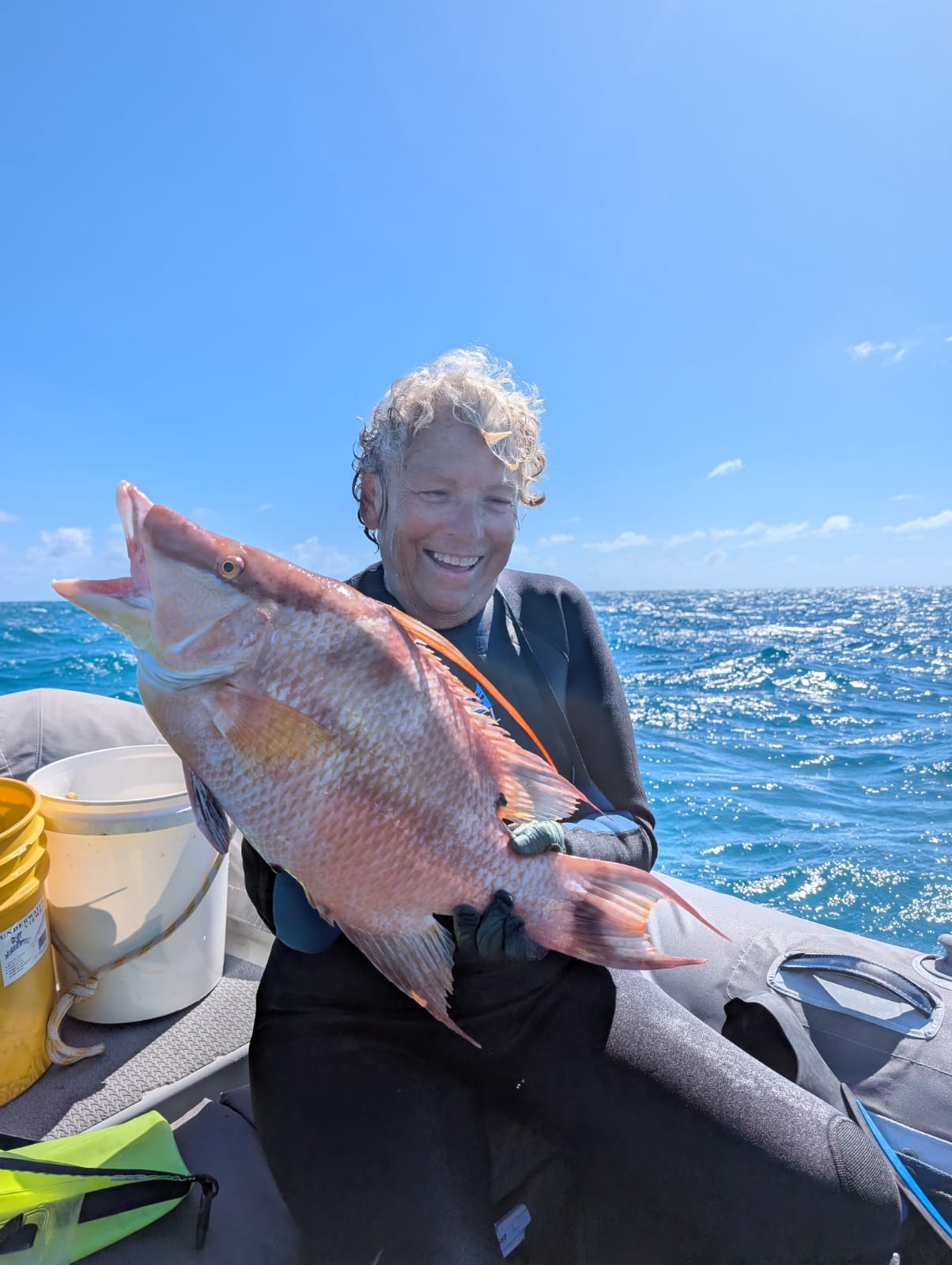 Smiling diver holding a large hogfish catch on the turquoise waters of the Ragged Islands Bahamas