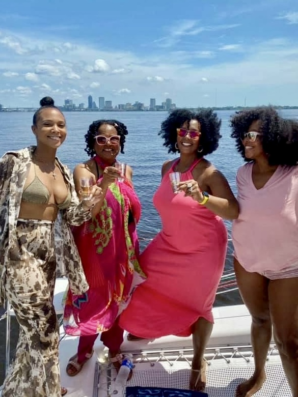 Group of women celebrating with champagne on Now and Zen catamaran with Jacksonville skyline
